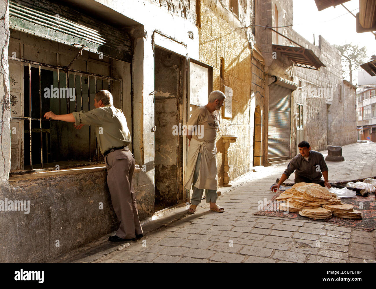 Außerhalb einer Backstreet-Bäckerei in der alten Stadt von Aleppo, Syrien, in den frühen Morgenstunden Stockfoto