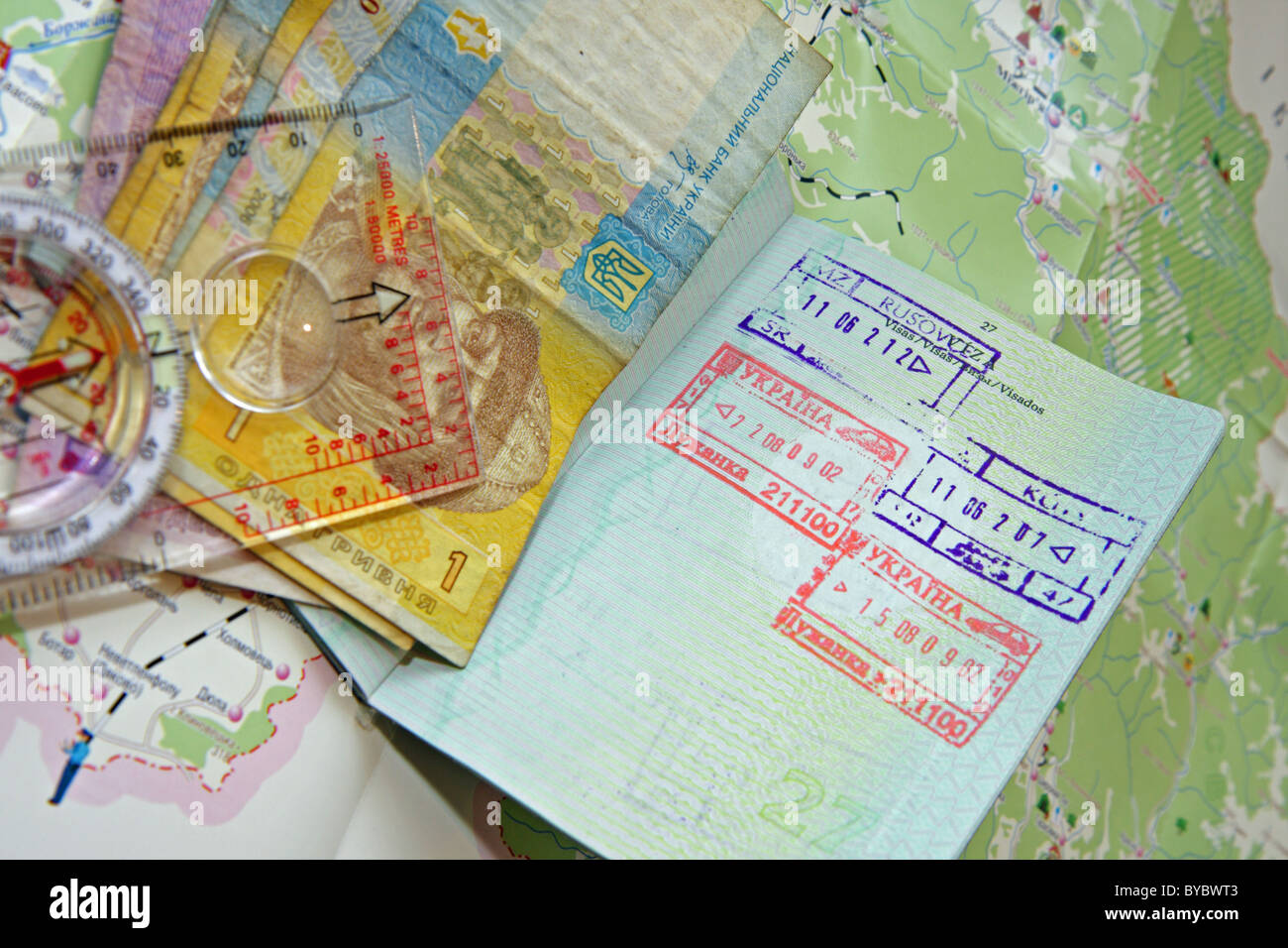 Reisepass mit ukrainischen Briefmarken, Banknoten und Kompass auf einer Karte od Ukraine Stockfoto