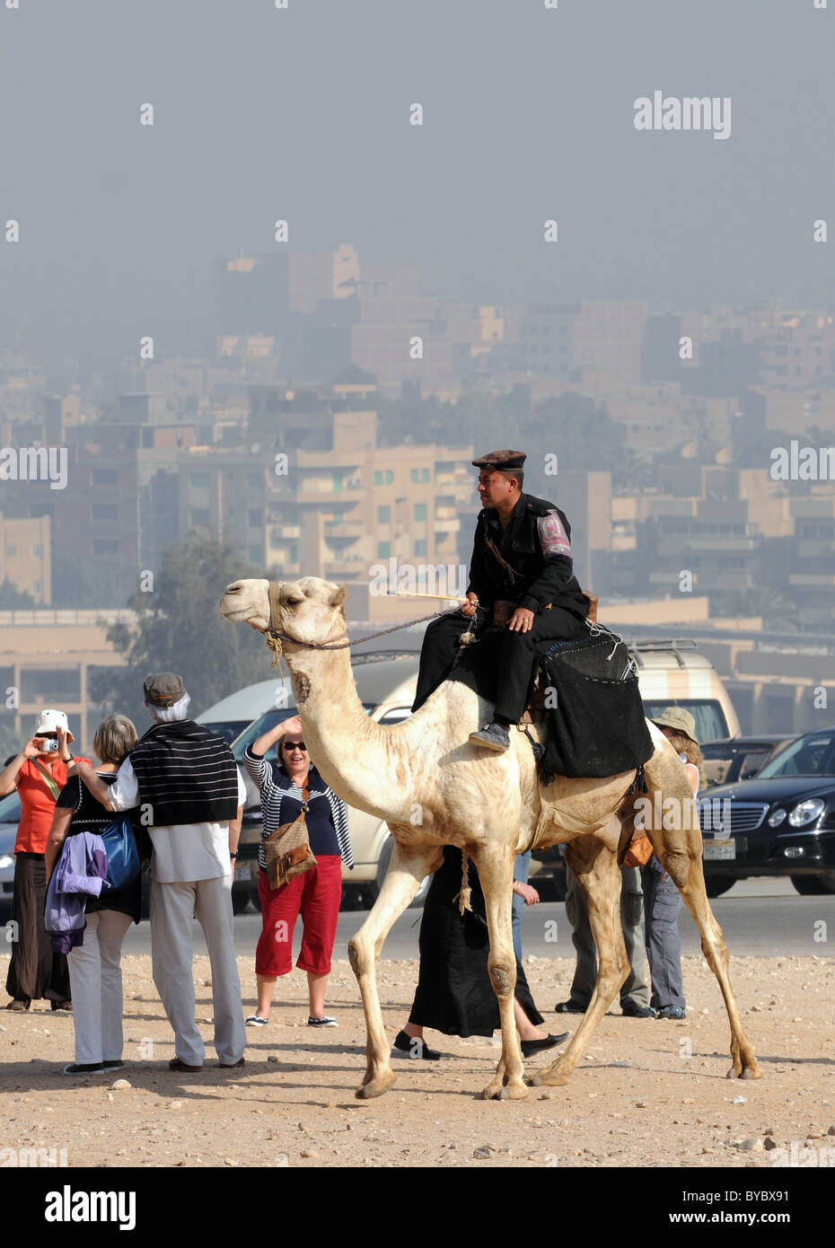 Polizei auf Kamelen und Touristen von Gizeh in Ägypten mit Kairo im Hintergrund. Stockfoto