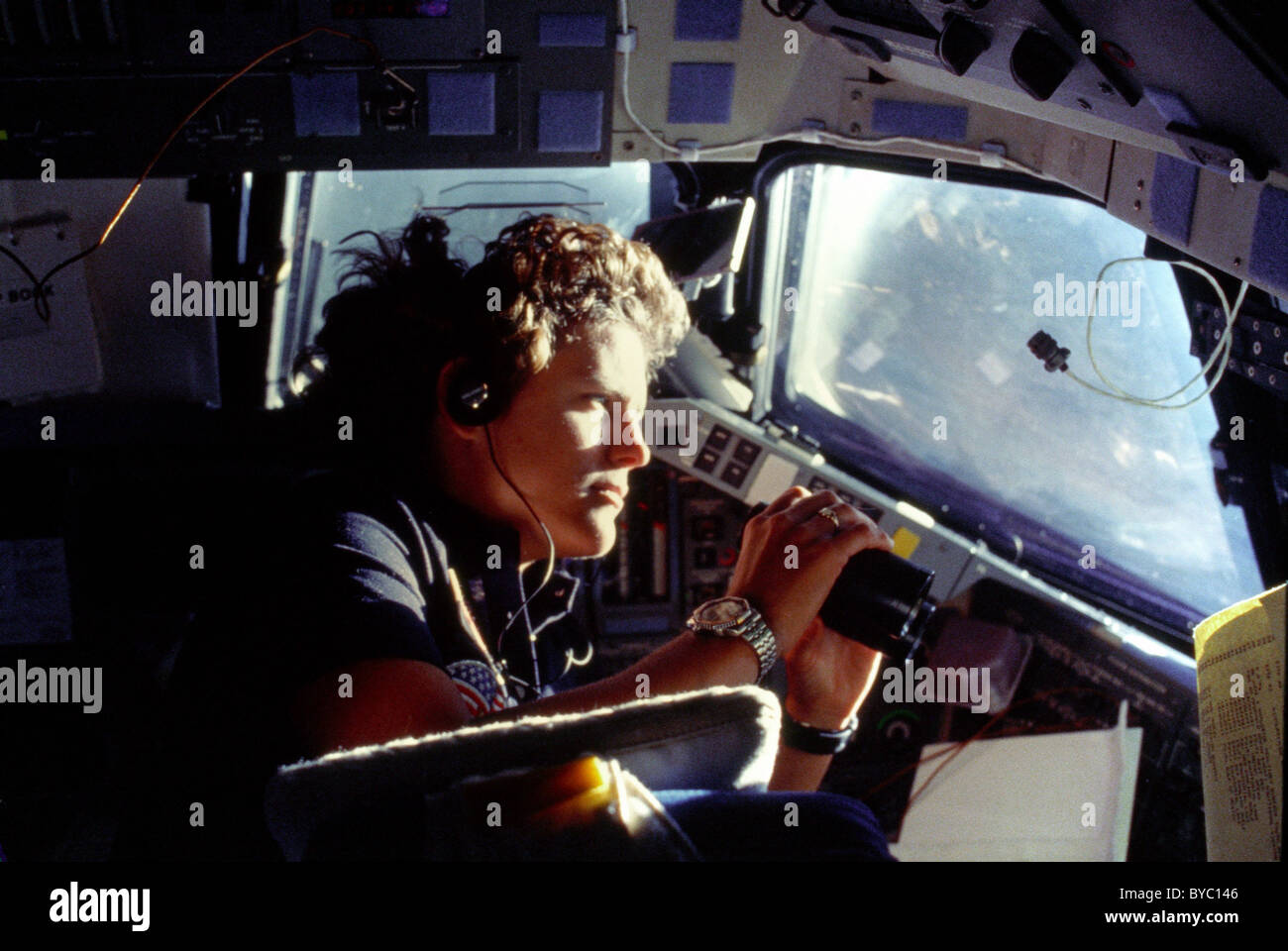 Astronaut Kathryn D. Sullivan nutzt Fernglas für eine vergrößerte Darstellung der Erde durch Herausforderers Bugkabine Fenster. Stockfoto