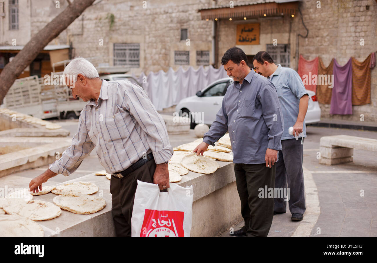 Syrische Männer trocknen ihr frisch gebackenes Brot an einer Wand im Zentrum von Aleppo, Syrien Stockfoto