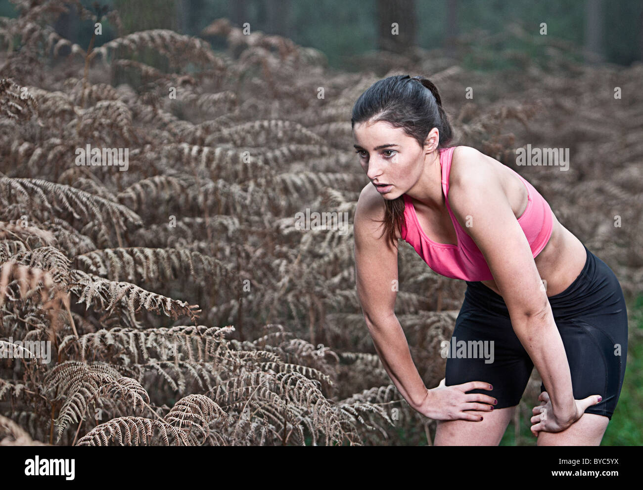 Weibliche Verschnaufpause vom Lauf im Wald Stockfoto