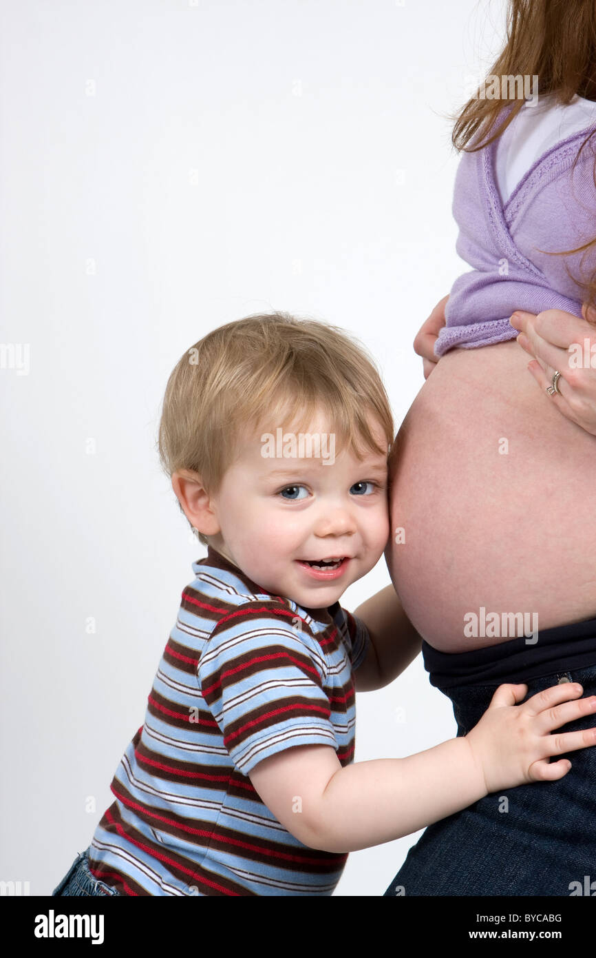 Ein kleiner Junge zu hören auf seine schwangere Mutter Bauch. Stockfoto