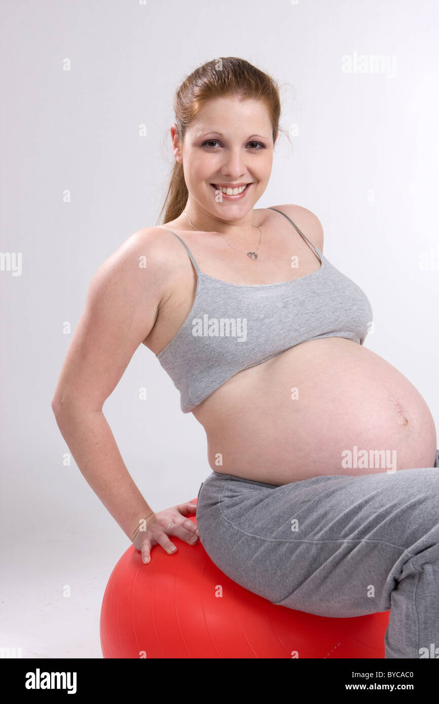 Eine schwangere Frau arbeitet auf einem Gymnastikball. Stockfoto