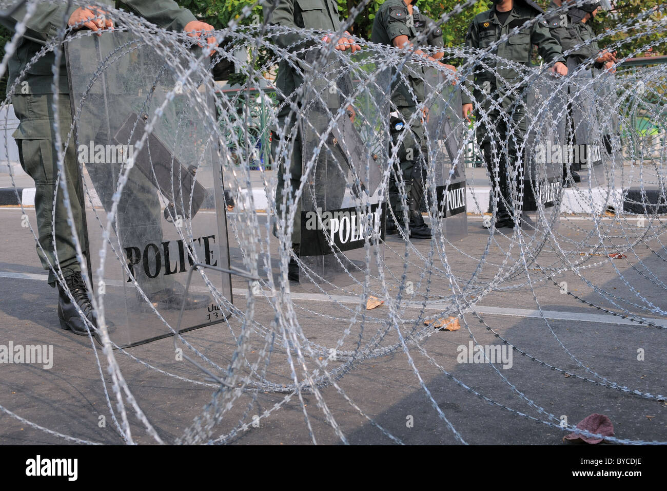 Bereitschaftspolizei hinter Stacheldraht bewachen einen Eingang zum Government House in Bangkok während einer großen Anti-Regierungs-gelb-Shirt-Kundgebung Stockfoto