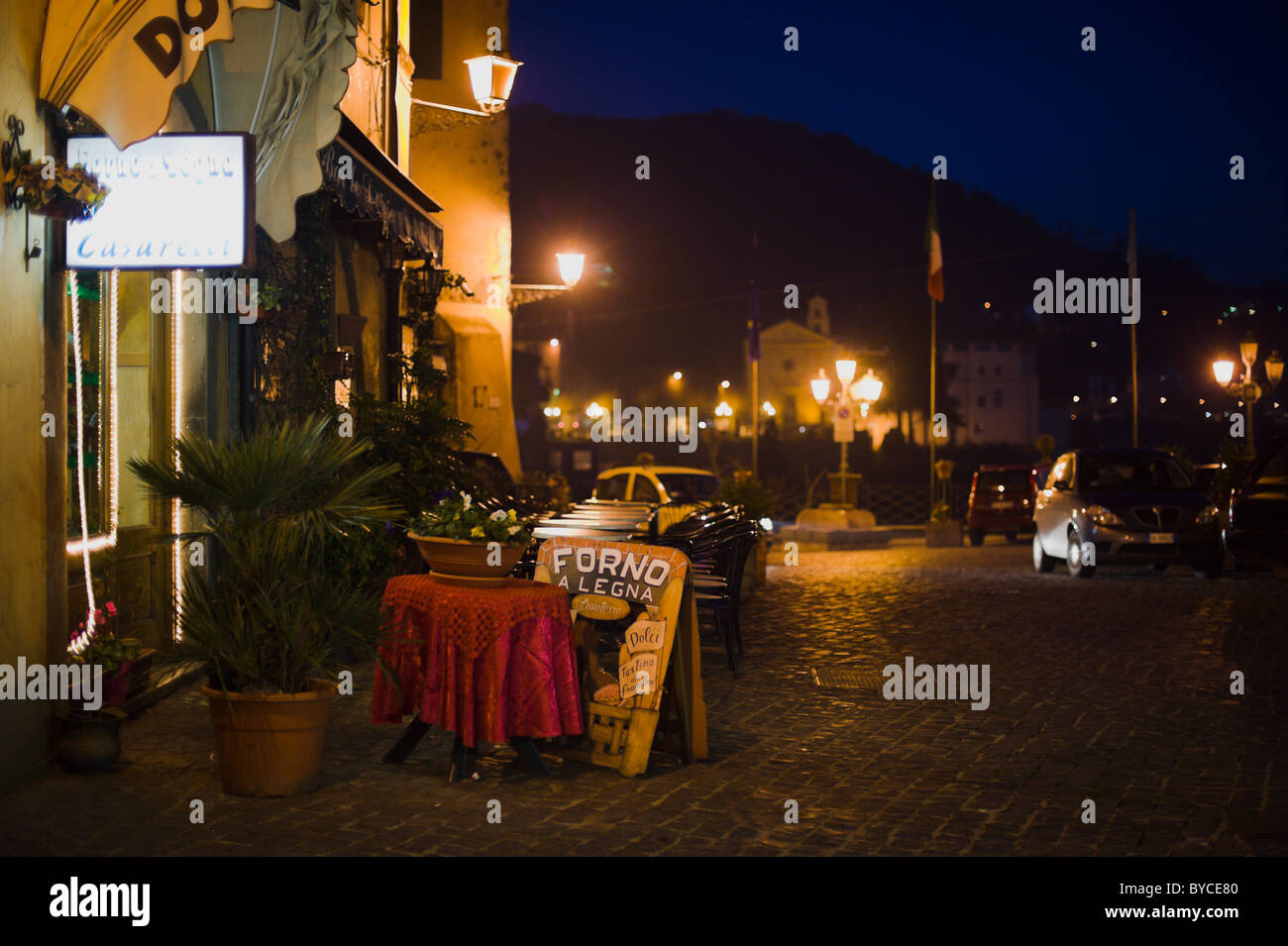 Nemi Höhenstraße mit Tischen im Freien, Geschäften und Straßenlaternen, in der Nacht Stockfoto