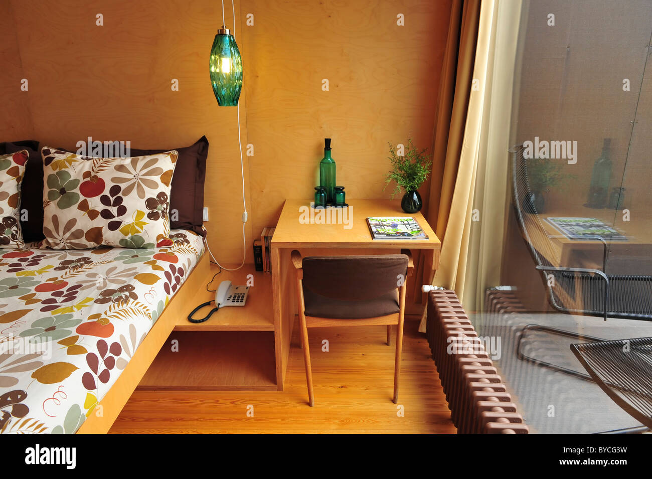 Eingestellt am Krankenbett grünes Glaslampe, Nachttisch mit Telefon, Gläser und Flasche, Stuhl, Fenster und Öl-Heizung Stockfoto