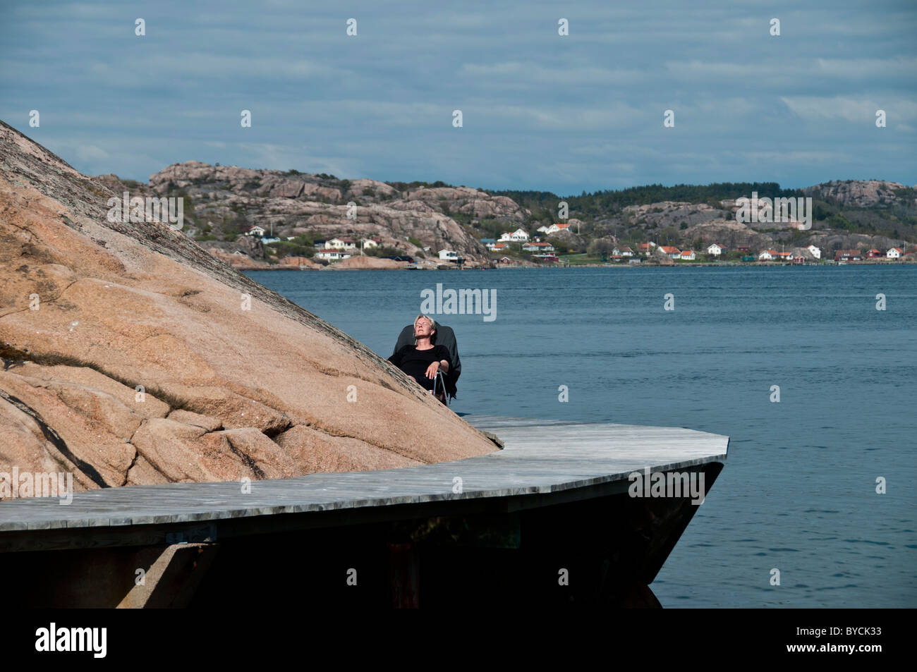 Eine Frau, die im Frühsommer Sonnenschein im Juni in Bovallstrand in Bohuslän an der West Küste Schwedens Stockfoto