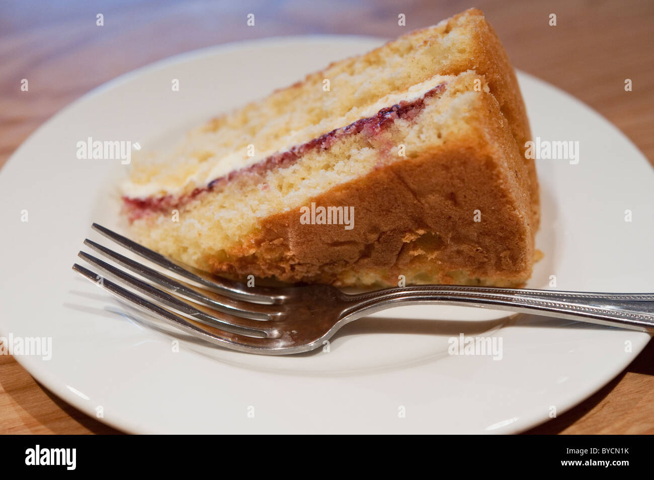 Eine Scheibe von Victoria Biskuit mit einer Gabel auf einem weißen Teller. Stockfoto