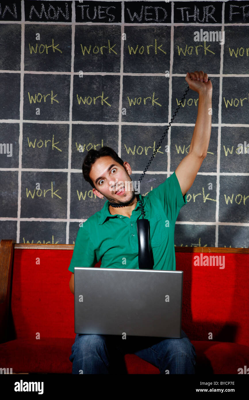 Frustrierten Büroangestellten überarbeitet Workaholic erwürgt sich Telefonkabel vor seinem Laptop. Stockfoto