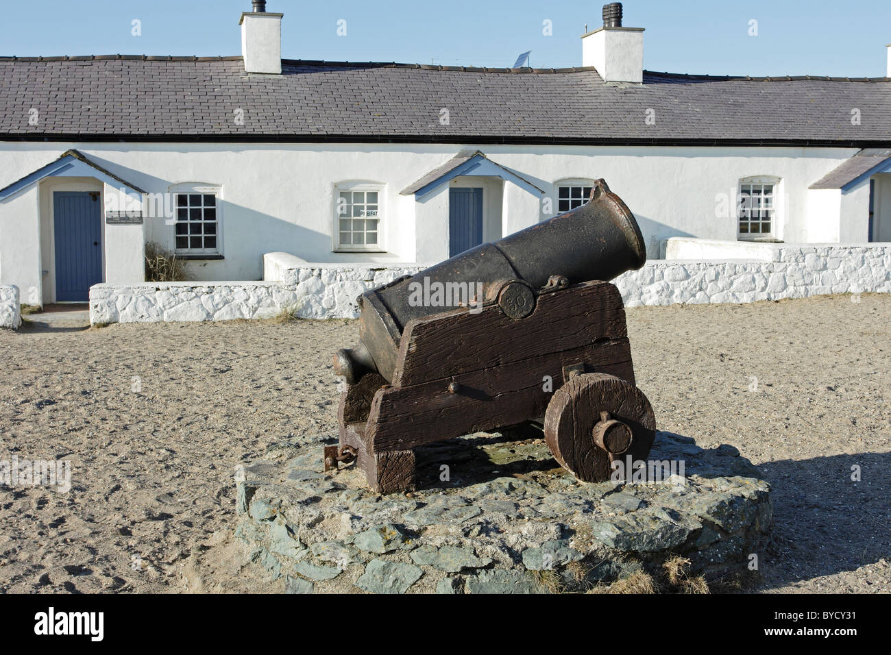 Eine Reihe von stillgelegten Piloten Hütten auf Llanddwyn Island, Anglesey, mit einem kastanienbraunen Kanon im Vordergrund Stockfoto