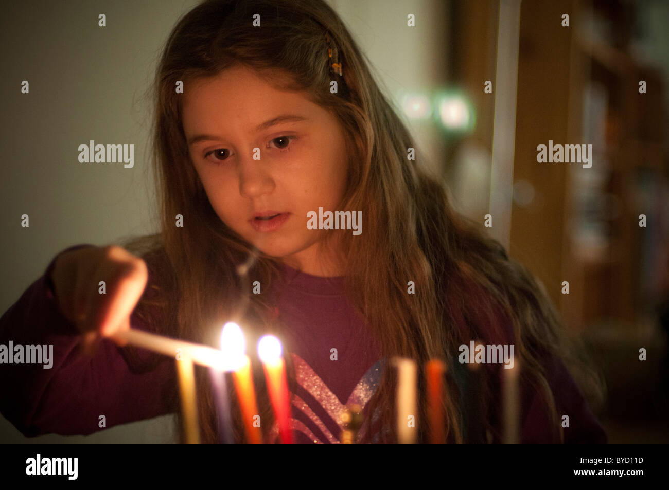 Ein junges Mädchen zündet Chanukka-Kerzen Stockfoto