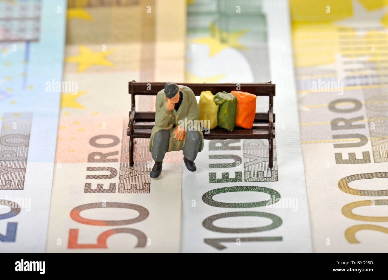 Verschiedenen Euro-Banknoten mit einem Miniatur-Wert von ein Obdachloser auf einer Parkbank, symbolisches Bild für die Euro-Währungskrise Stockfoto