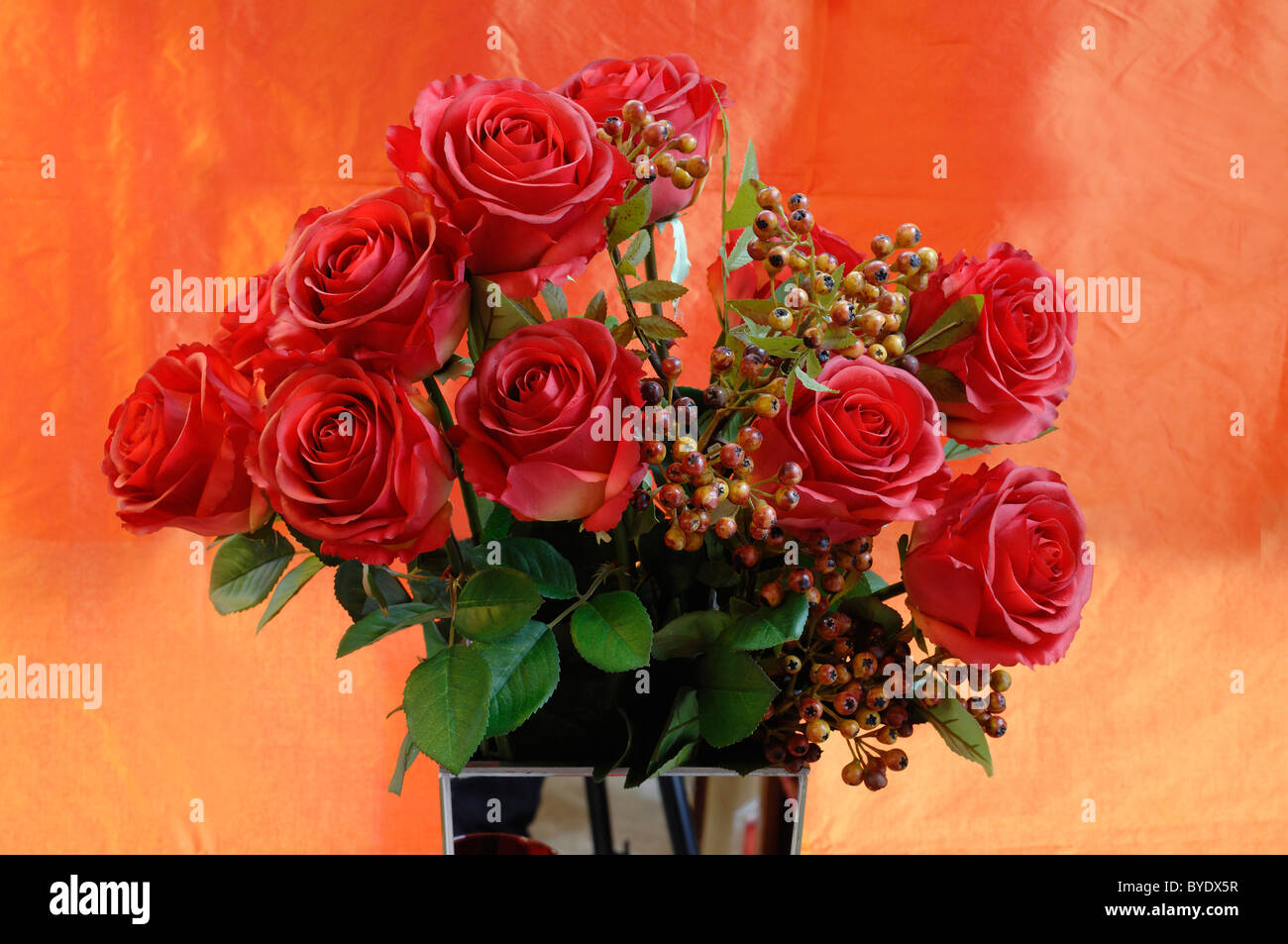 Künstliche rote Seide Rosen in einer Vase vor orange Tuch, Villa & Ambiente, Nürnberg, Middle Franconia, Bayern Stockfoto