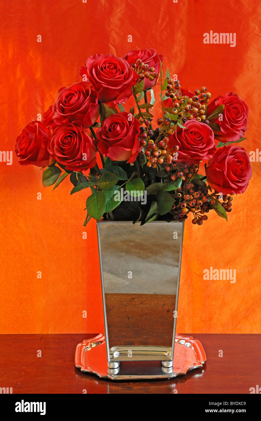 Künstliche rote Seide Rosen in einer Vase vor orange Tuch, Villa & Ambiente, Nürnberg, Middle Franconia, Bayern Stockfoto