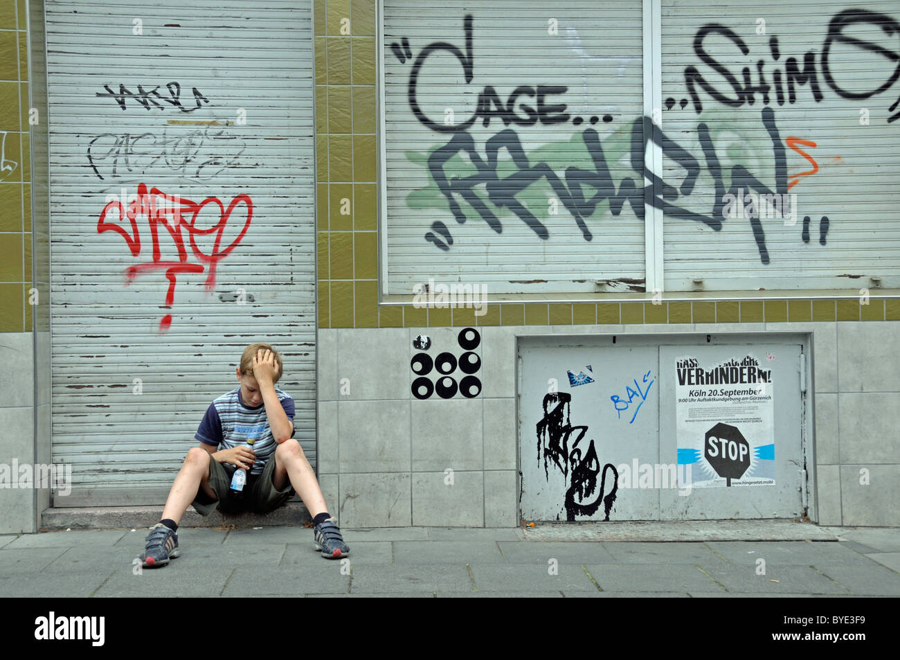 Allein neun Jahre alten Jungen vor einem geschlossenen Geschäft die mit Graffiti, Deutschland, Europa verschmiert ist Stockfoto