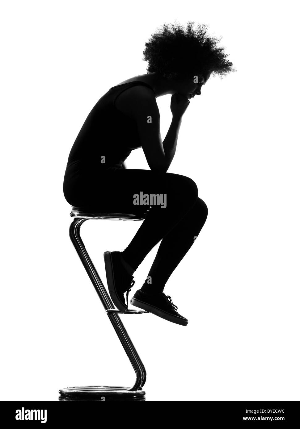 schöne lustige junge Afro Amerikanerin sitzt auf Schemel nachdenklich in Silhouette Schatten auf weißem Hintergrund Studio isoliert Stockfoto