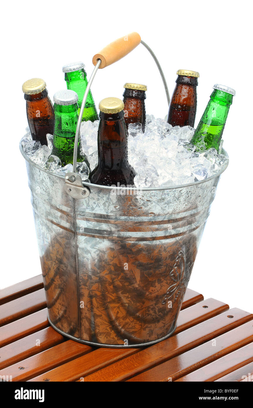 Bier Eimer gefüllt mit verschiedenen Flaschen und Eiswürfel auf Teak Tisch vor einem weißen Hintergrund. Stockfoto