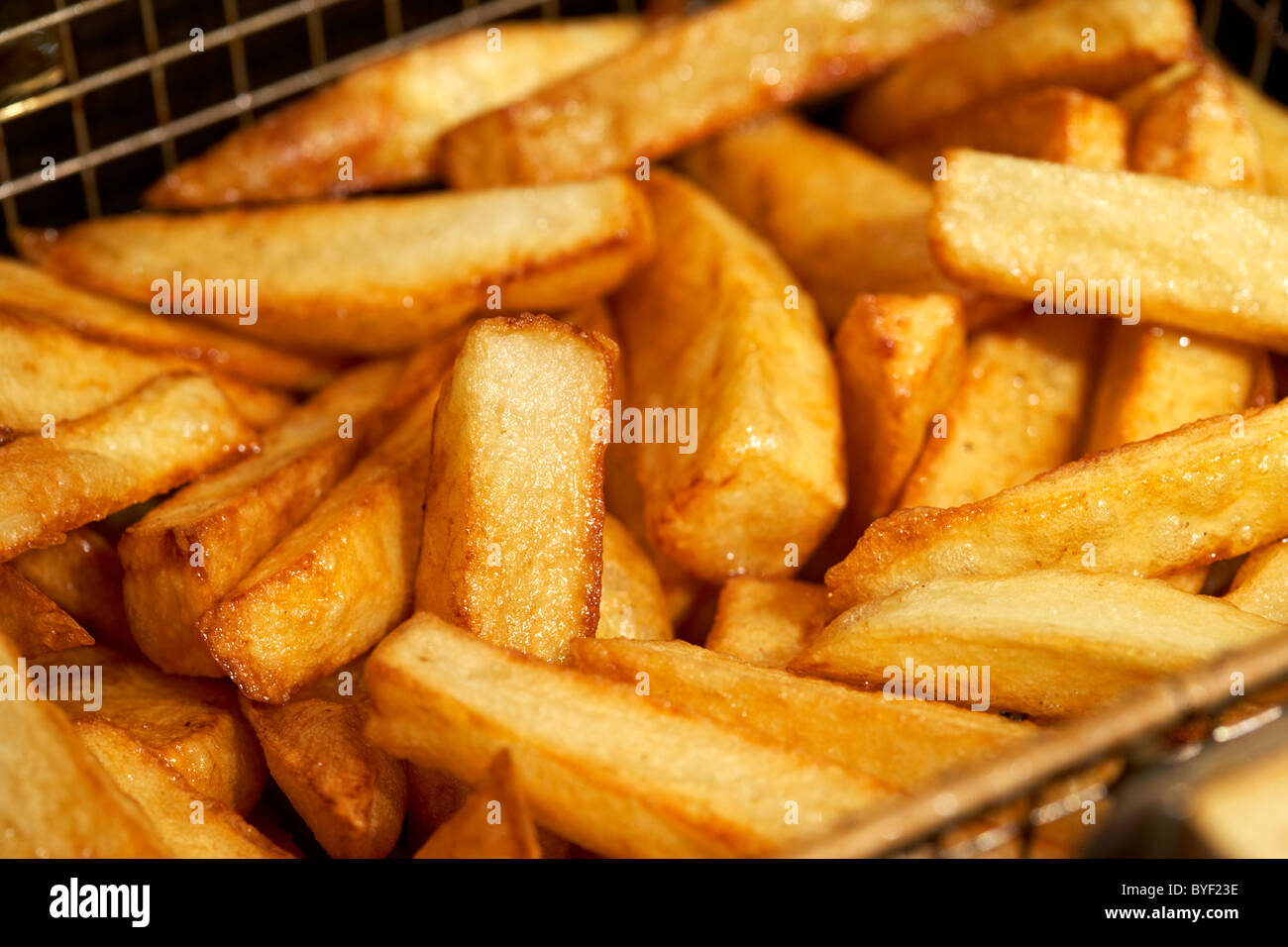 goldbraun gekocht frisch hausgemachten Chips hergestellt aus irischen Kartoffeln in ein tiefes Fett Friteuse Korb Stockfoto