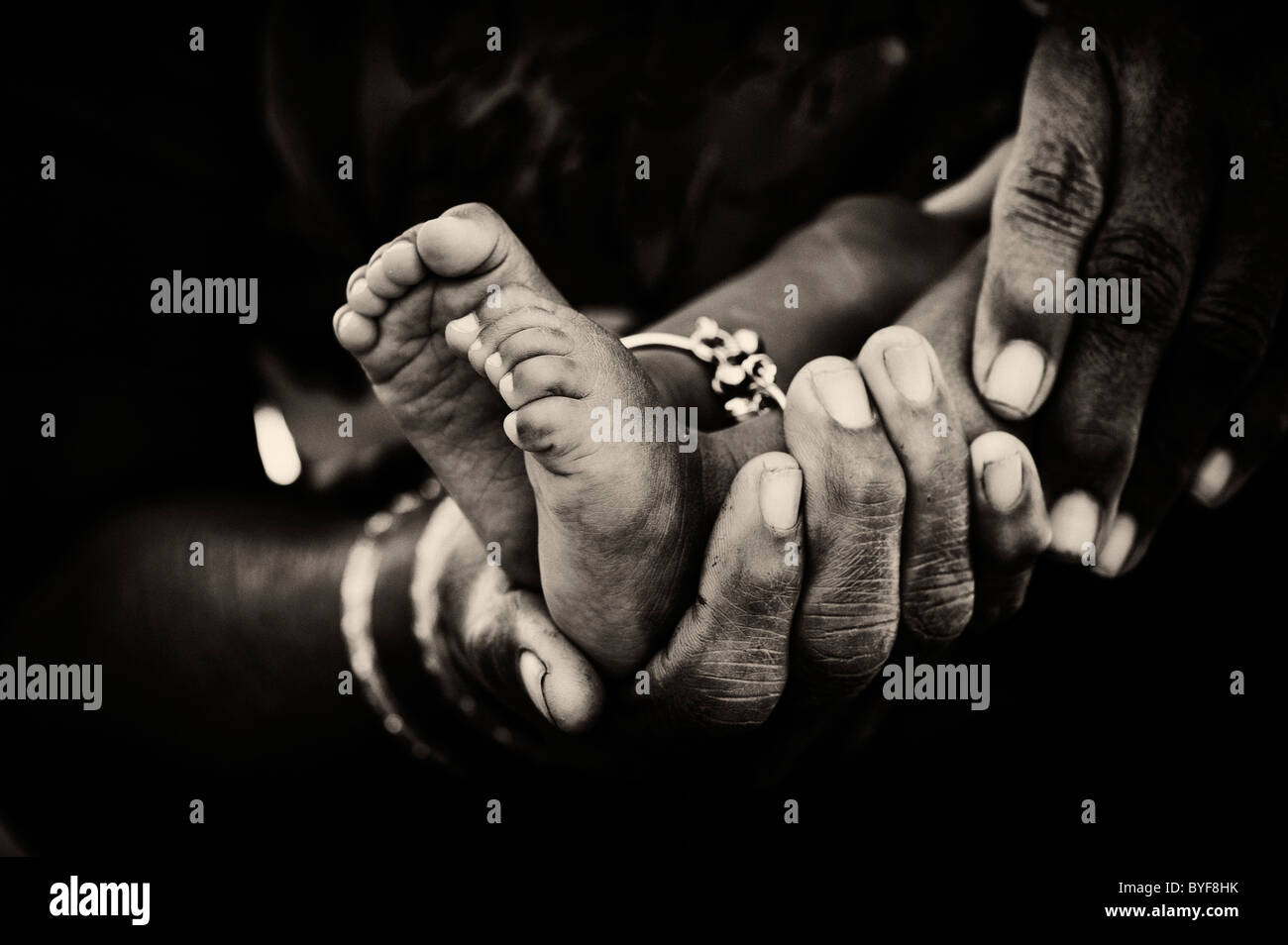 Indische Großmutter Hände und Babys nackten Füßen. Monochrom Stockfoto