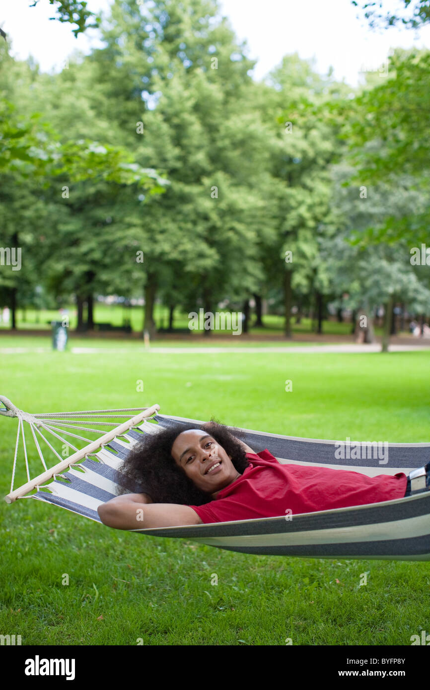 Junger Mann mit Afro-Haar liegen in der Hängematte im park Stockfoto