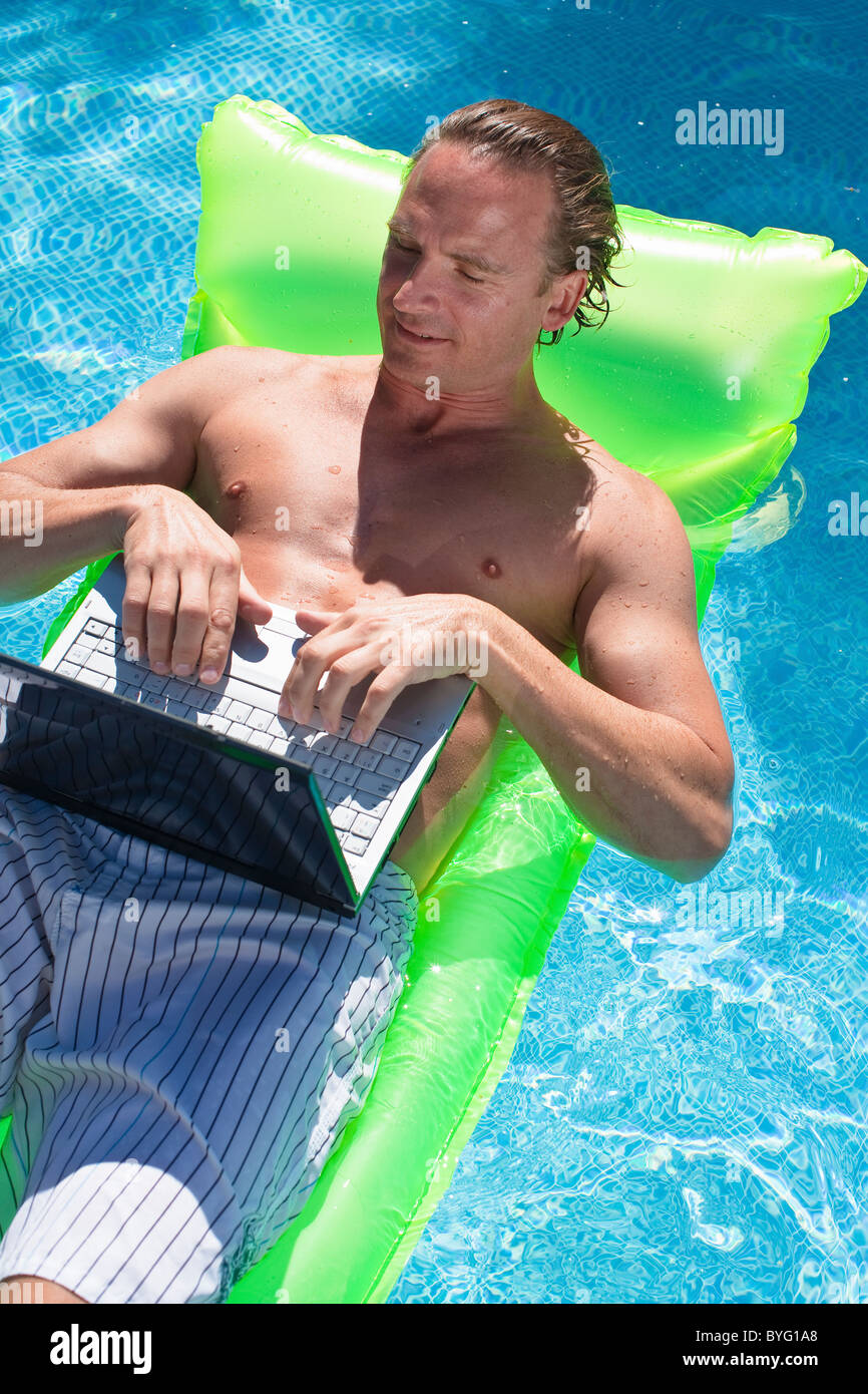 Man schwimmt auf Schlauchboot und arbeiten am laptop Stockfoto