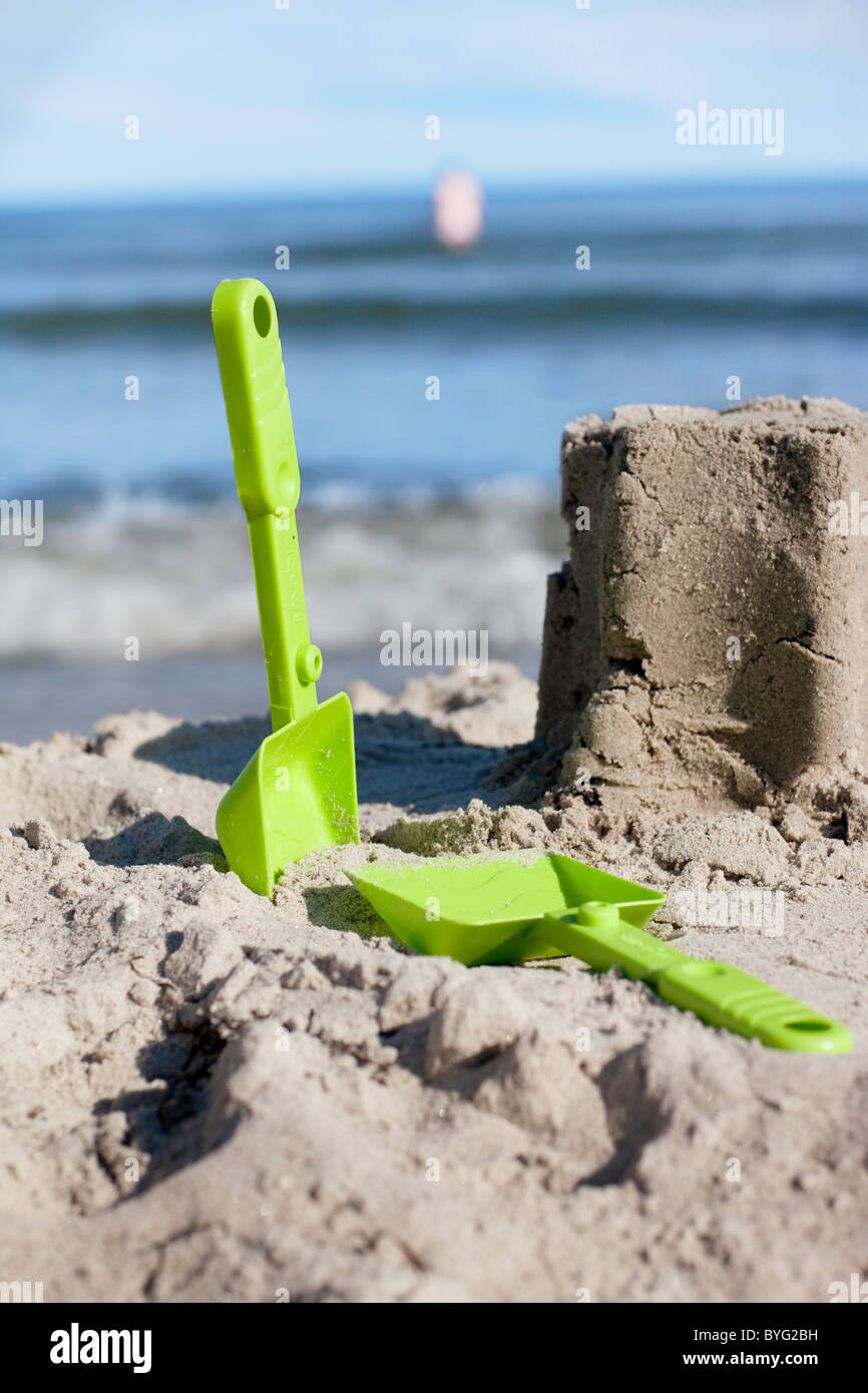 Kunststoff Schaufeln und Sandburg am Strand Stockfoto