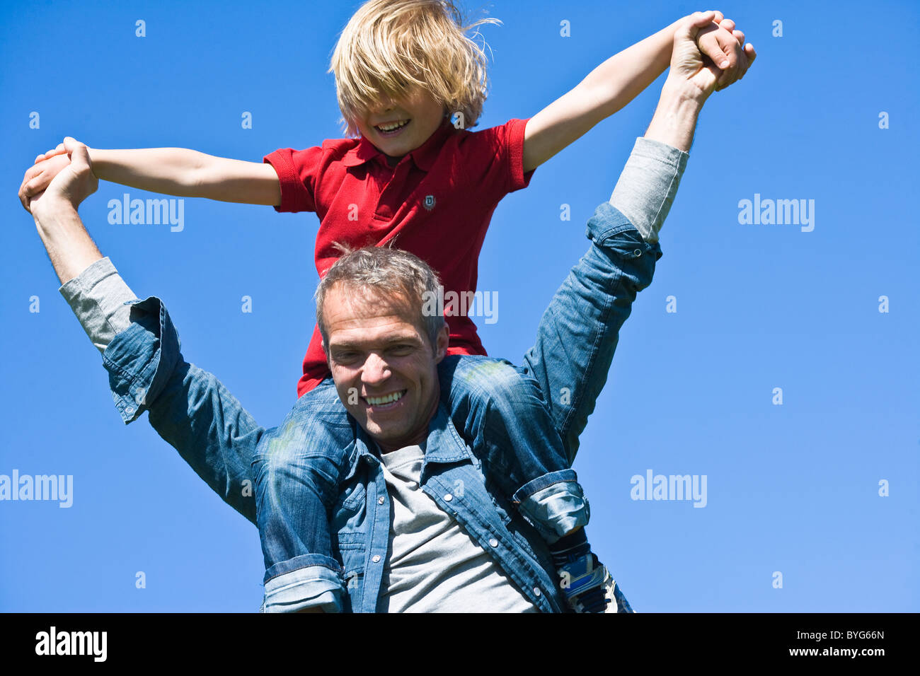 Huckepack Porträt von Vater und Sohn gegen klaren Himmel in hellem Sonnenlicht Stockfoto
