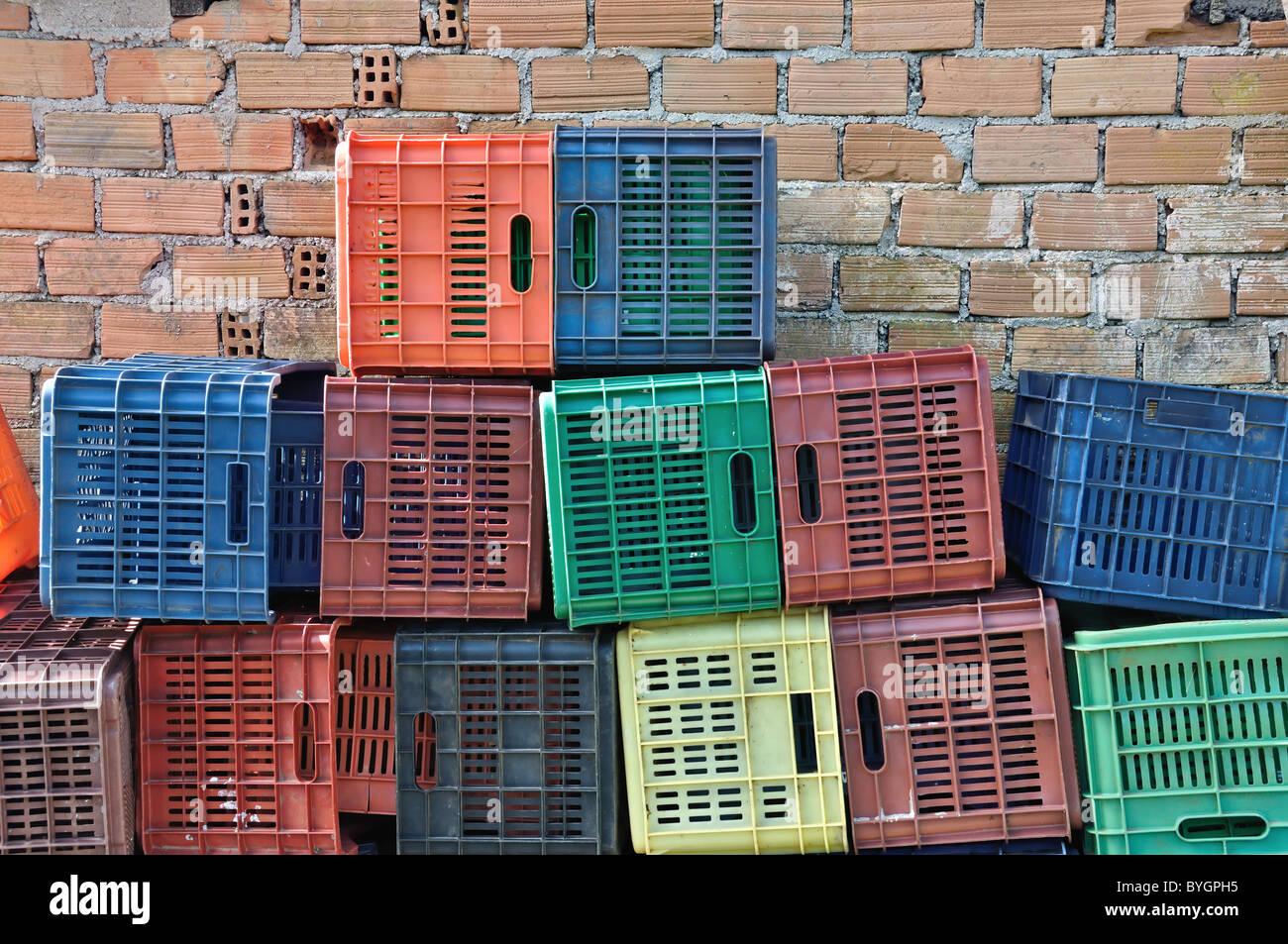 Kunststoffkisten und Ziegel Wand Hintergrund. Haufen von bunten Obst Container packen. Stockfoto