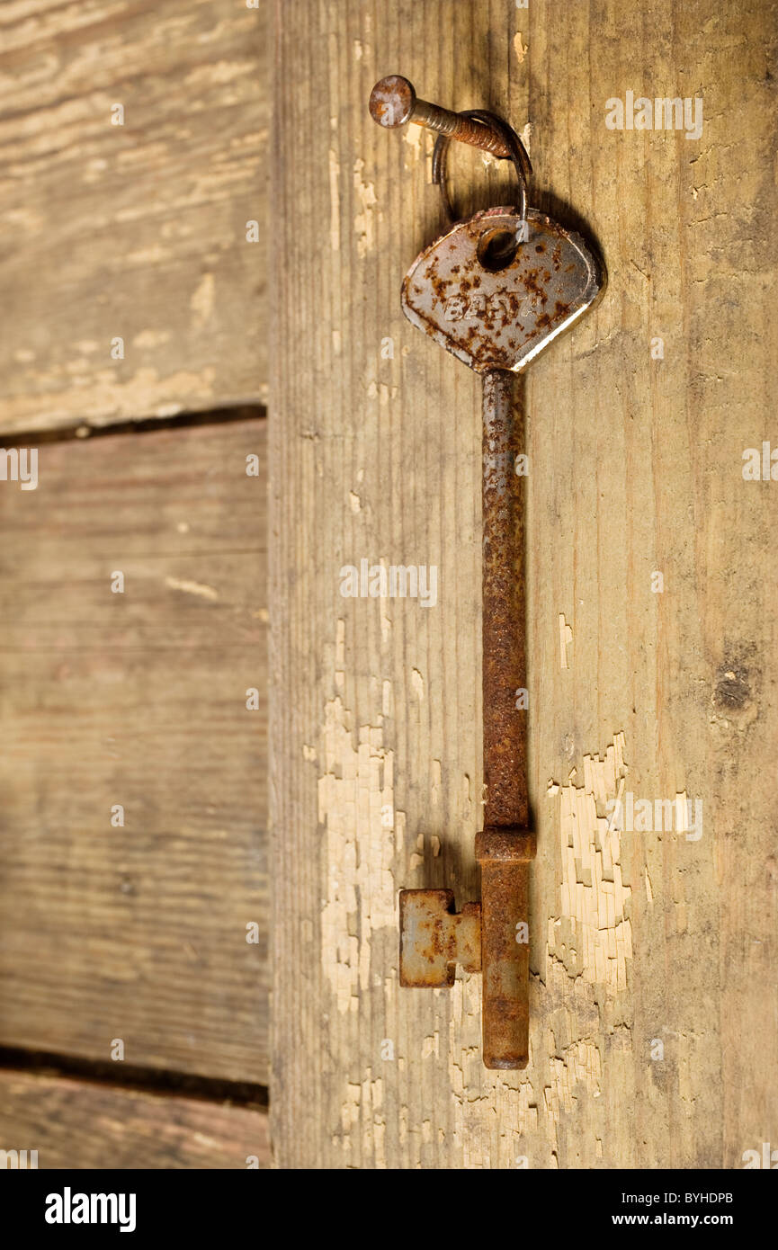 Eine rostige alte Schlüssel hängt an einem Nagel Stockfoto