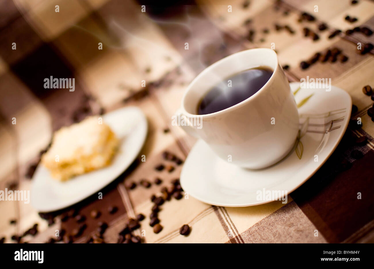 Sehr heißer Kaffee Tasse und Kuchen auf den Tisch, Kuchen in der Hintergrund jedoch unscharf Stockfoto