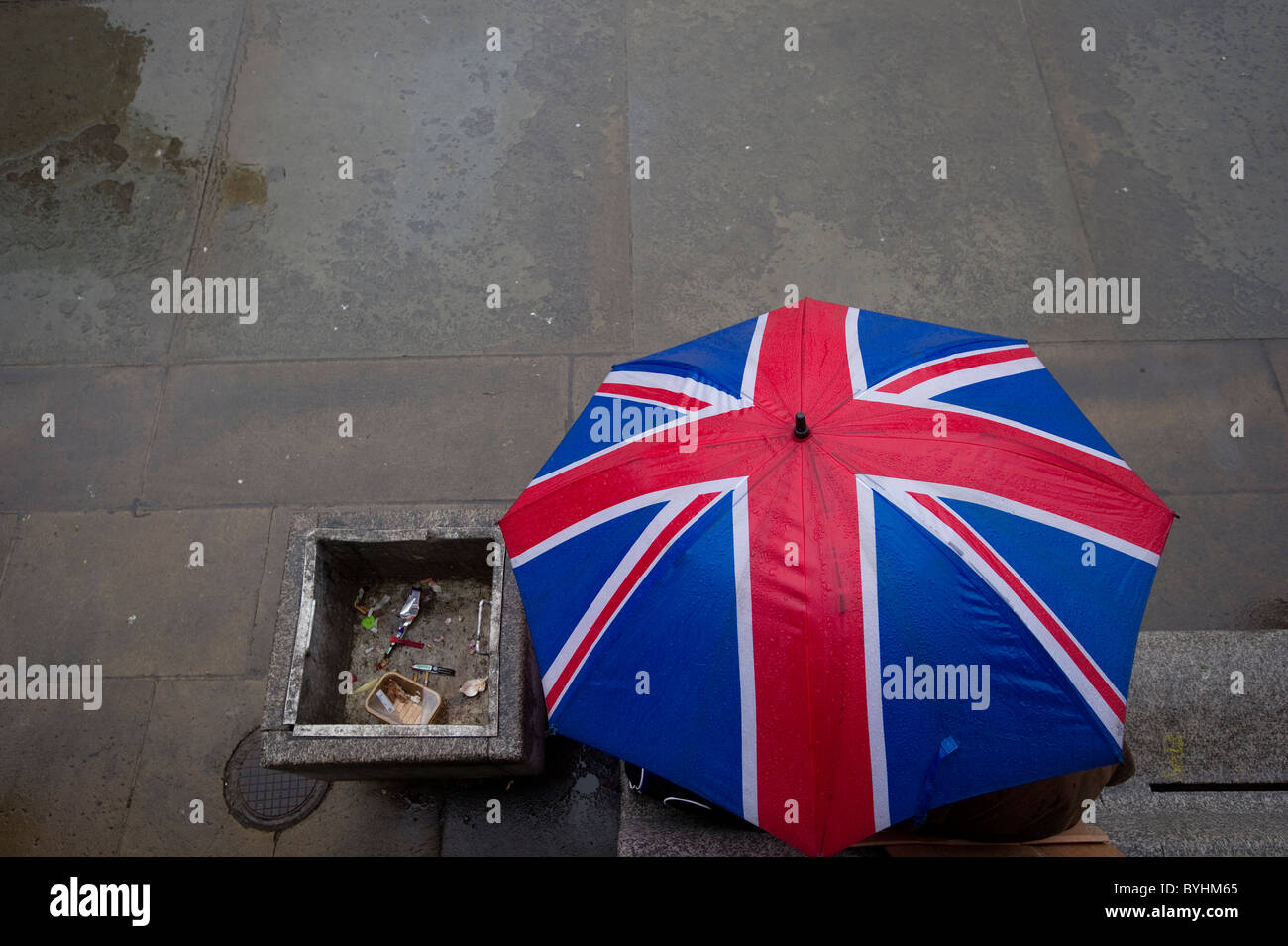 Eine Person Schutz vor dem Regen unter ein Dach Anschluß-Markierungsfahne am Trafalgar Square in central London. Stockfoto