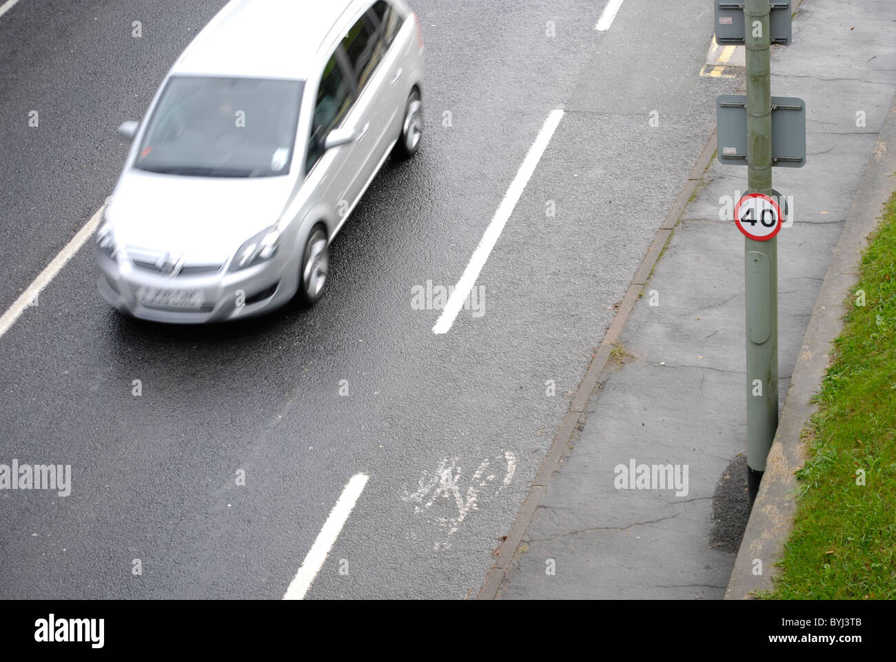 Auto mit Motion blur durch 40 km/h-Abschnitt der Straße entlang eines markierten Radweg fahren. Stockfoto