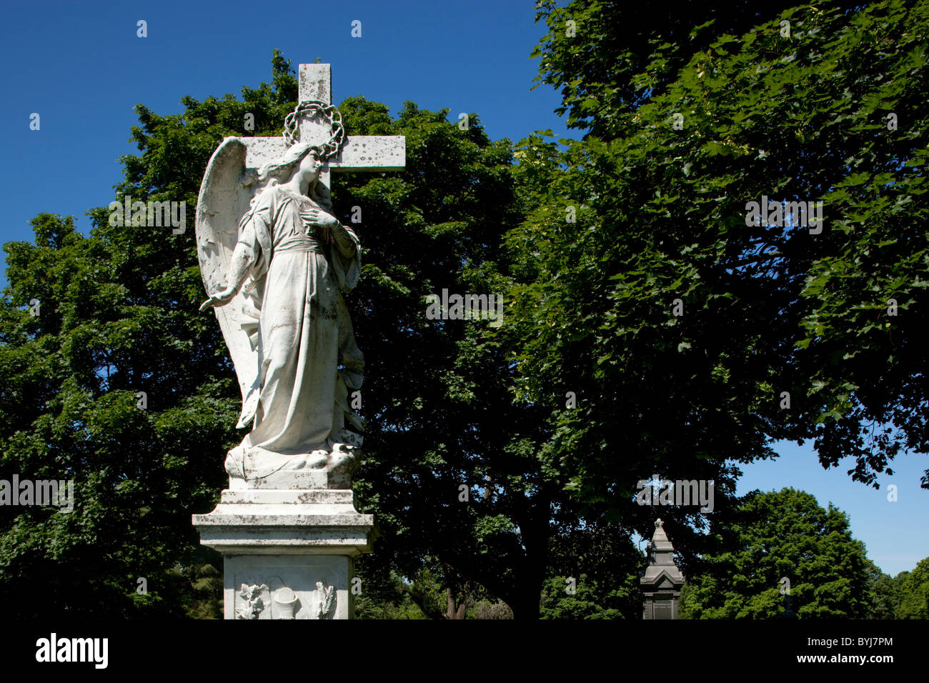 Statue von Christian Engel und Kreuz auf Grab im Friedhof am Sommermorgen, Lowell, Massachusetts, USA Stockfoto