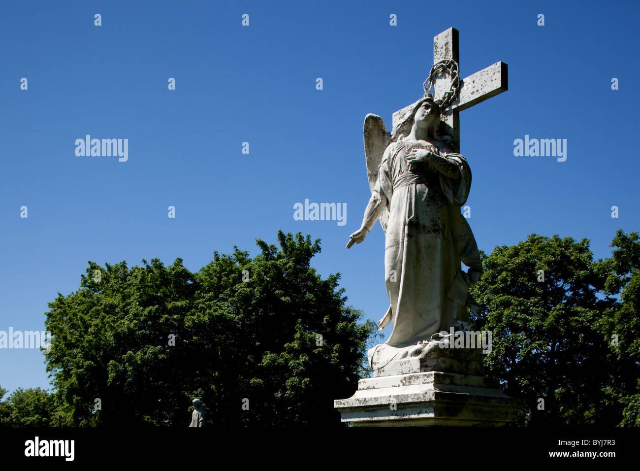 Statue von Christian Engel und Kreuz auf Grab im Friedhof am Sommermorgen, Lowell, Massachusetts, USA Stockfoto