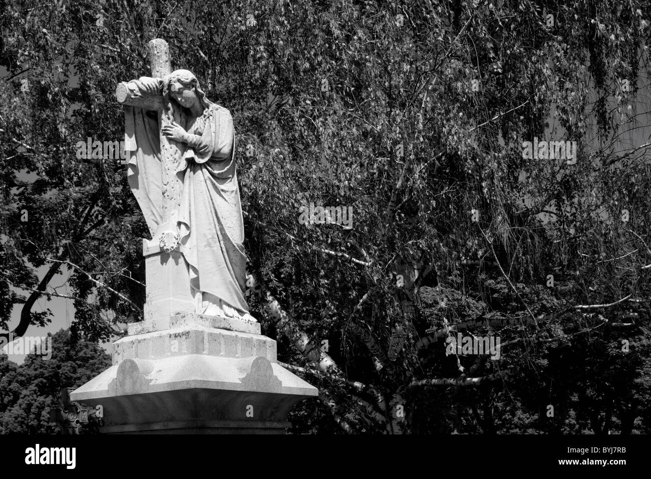 Statue von Christian Engel und Kreuz auf Grab im Friedhof am Sommermorgen, Lowell, Massachusetts, USA Stockfoto