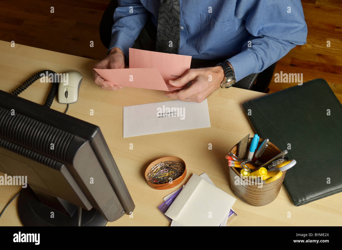 Geschäftsmann am Schreibtisch hält Pink-slip Stockfoto