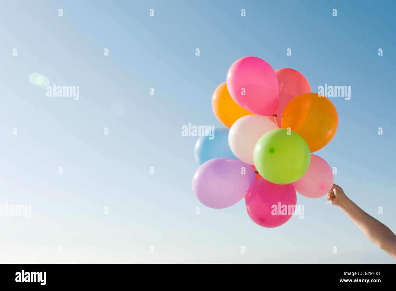 Bündel von Helium-Ballons gegen strahlend blauen Himmel empor gehalten. Stockfoto