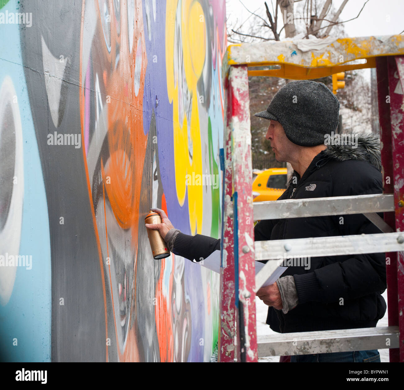 Der Künstler Kenny Scharf repariert sein Wandbild an der Ecke Bowery und Houston Street in New York Stockfoto