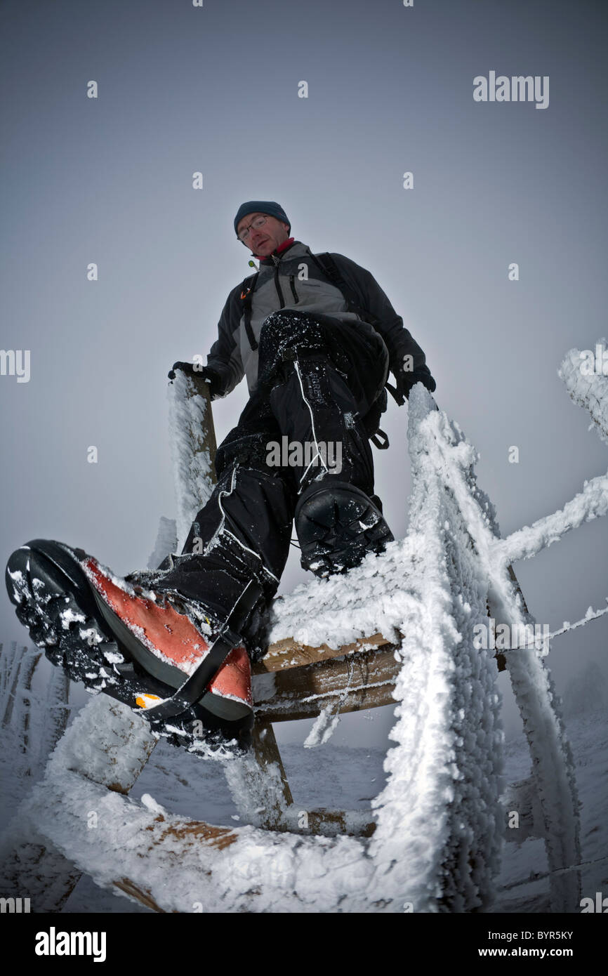 Im Winter ist ein Wanderer Klettern einen Stil in der Auvergne Vulkane Nature Reserve (Frankreich).  Randonneur Franchissant un Échalier. Stockfoto