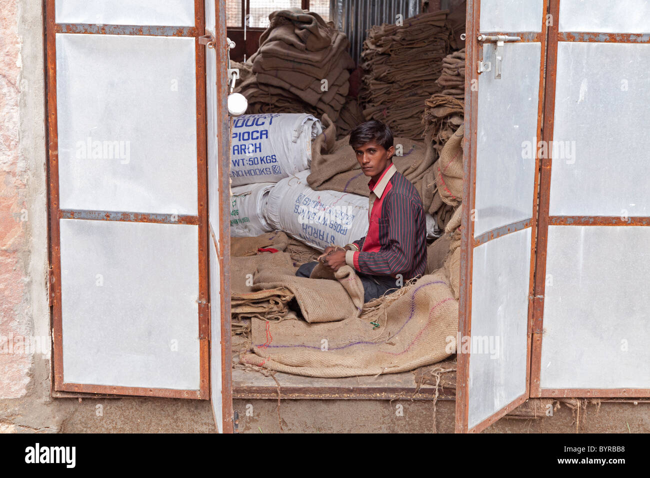 Indien, Rajasthan, Jüngling Jodhpur Reparatur hessische Säcke umrahmt von Metall Fensterläden Stockfoto