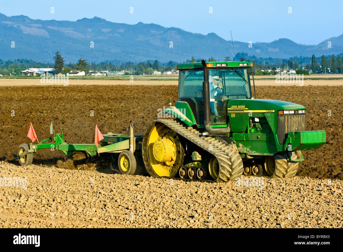 Ein John Deere verfolgt Traktor ziehen einen reversiblen Pflug bereitet ein Feld für die Bepflanzung Kartoffeln / in der Nähe von Burlington, Washington, USA Stockfoto
