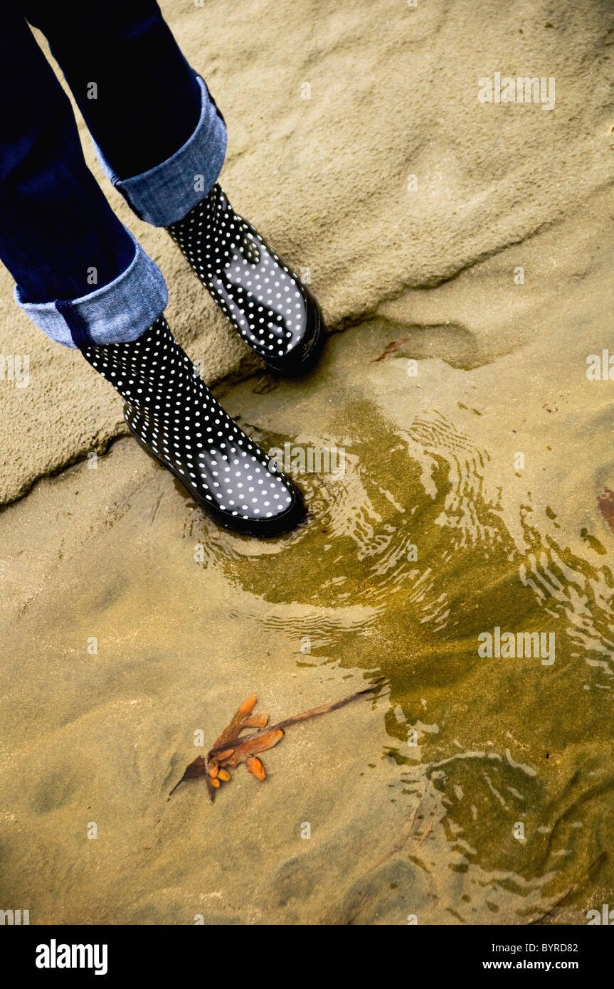 eine Frau Gummistiefel im Wasser gespiegelt; Seattle, Washington, Vereinigte Staaten von Amerika Stockfoto