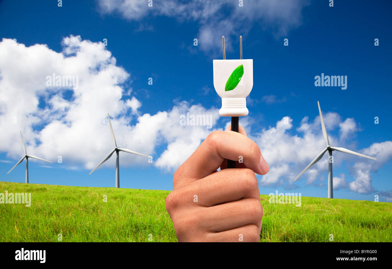 Hand halten Öko-Netzstecker und Eco Windkraftanlage auf blauen Himmel Stockfoto
