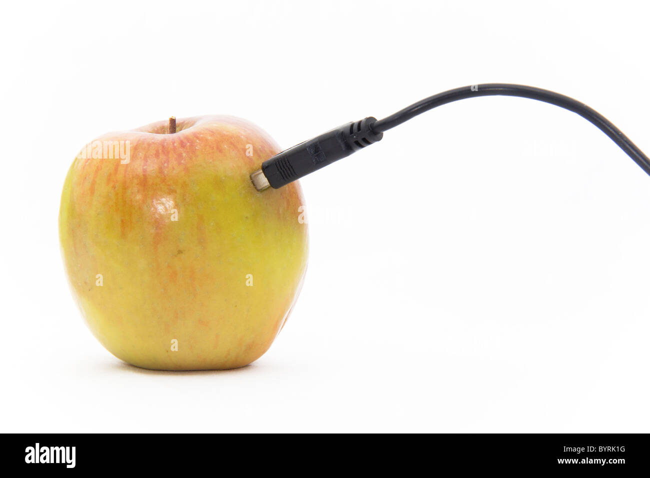 Einen eigentlichen Apfel steckte in ein USB-Kabel auf einem weißen Hintergrund Stockfoto