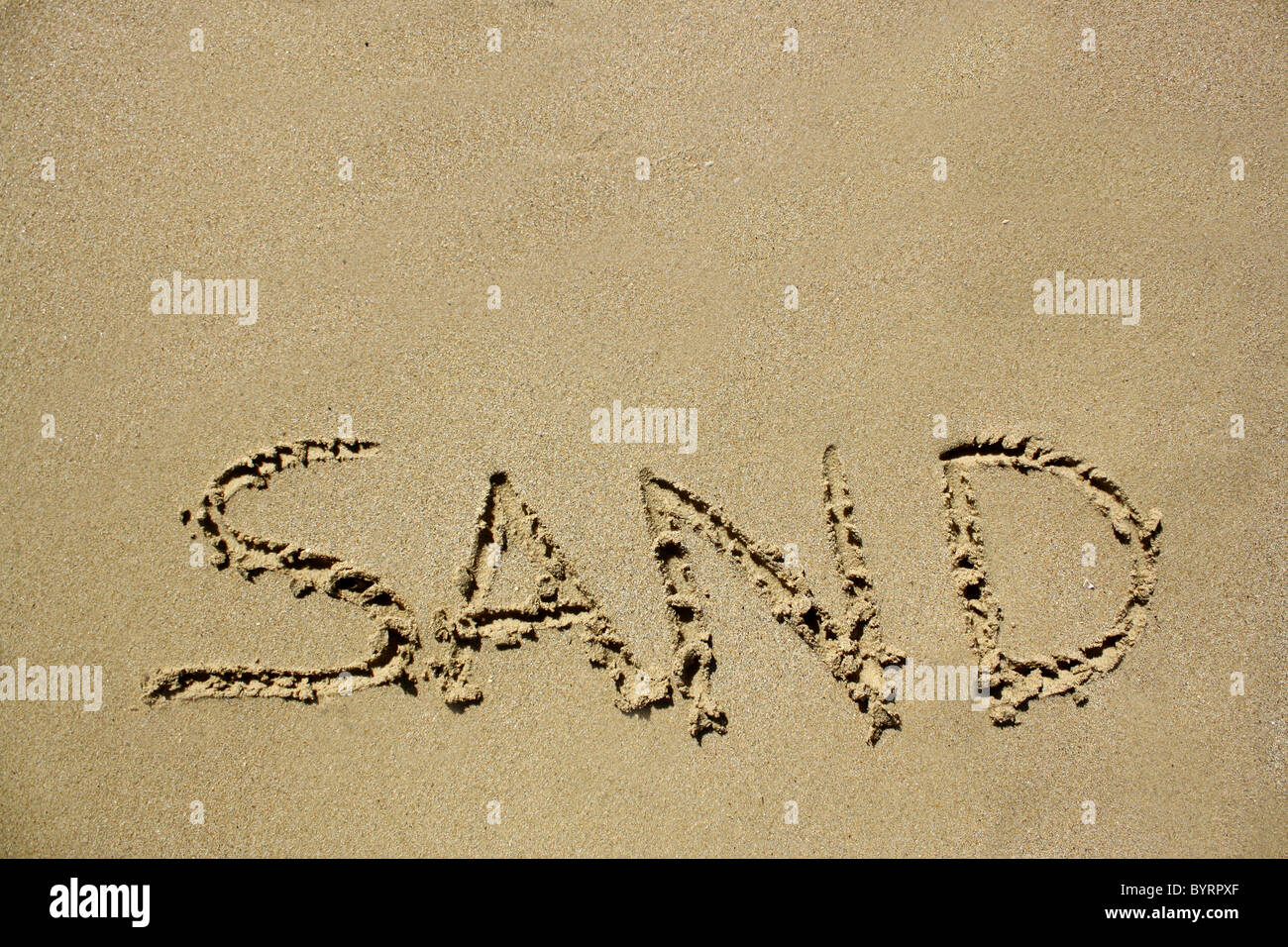 "Sand" im nassen Sand ausgeschrieben. Bitte siehe meine Sammlung ähnlicher Fotos. Stockfoto