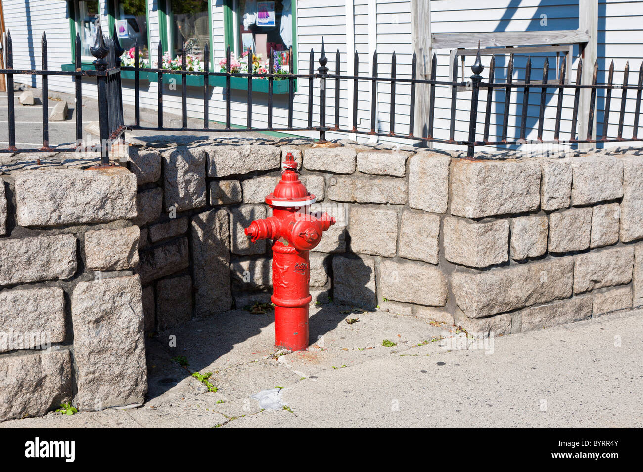 Ausschnitt in Granit Stein Mauer um einen leuchtend roten Hydranten auf der Main Street in Bar Harbor, Maine Stockfoto