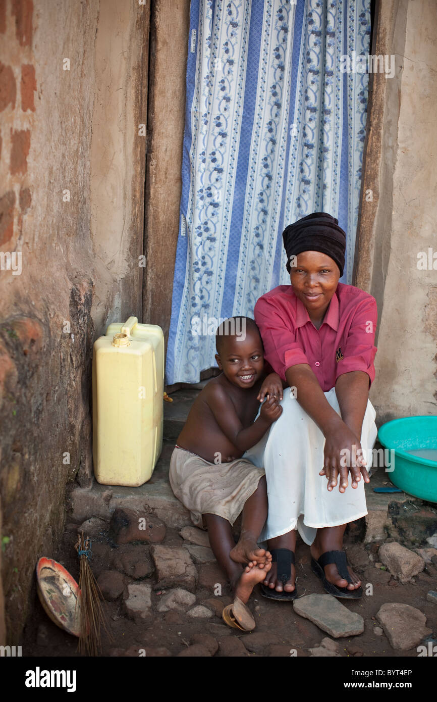 Eine junge urbane HIV positive Mutter und Kind sitzen vor ihrem Haus in Kampala, Uganda, Ostafrika. Stockfoto