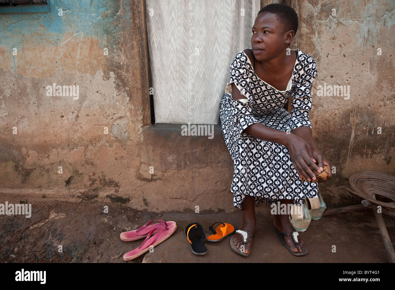 Eine junge, urbane Frau sitzt draußen vor ihrer Haustür in Kampala, Uganda, Ostafrika. Stockfoto
