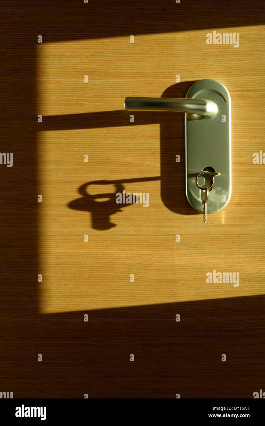 Schlüssel im Türschloss wirft einen langen Schatten Stockfoto